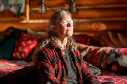 A woman with a red plaid jacket sitting and meditating in a log home